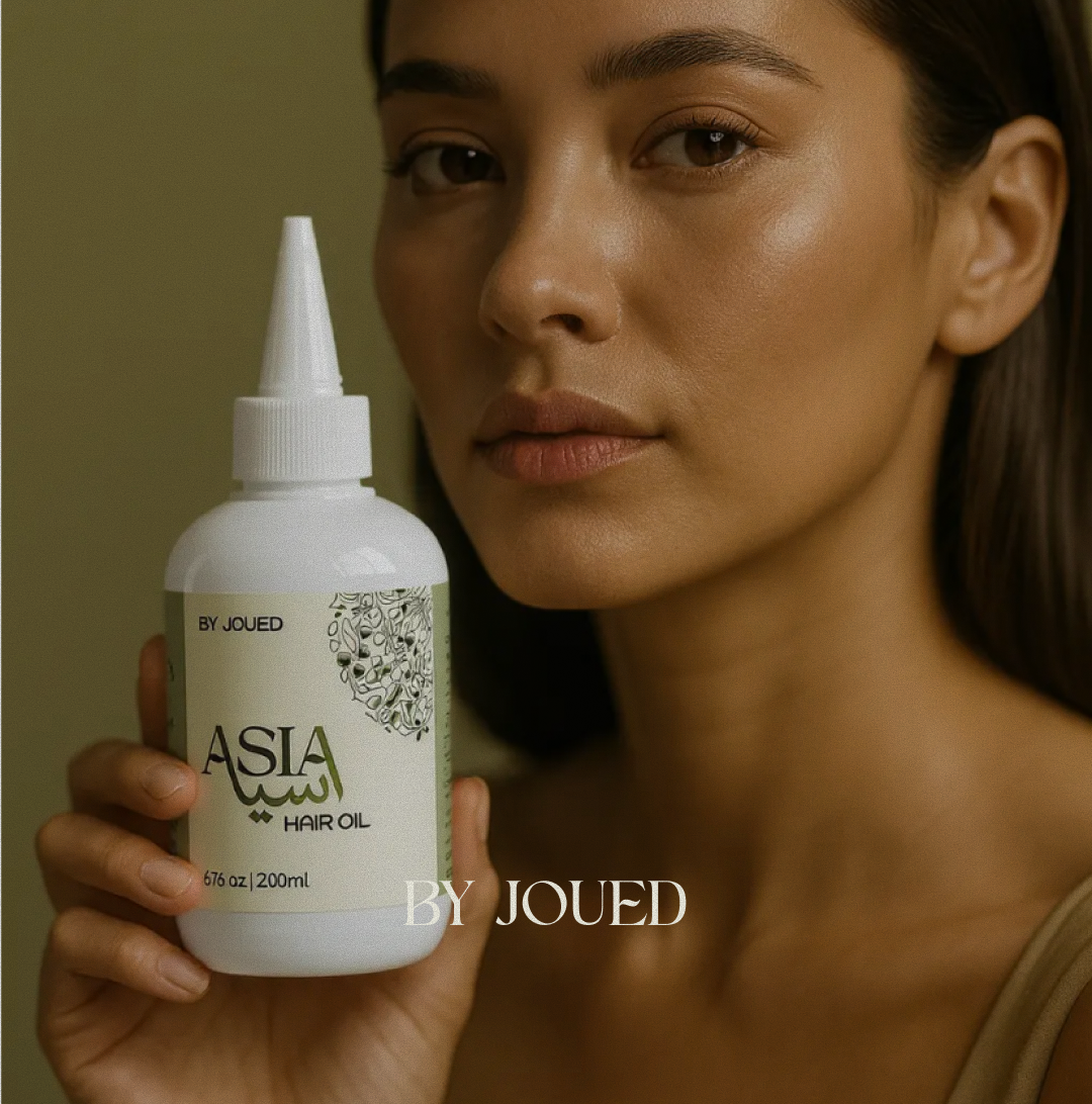 Woman holding a bottle of 'Asia' hair oil by Joued against a neutral background